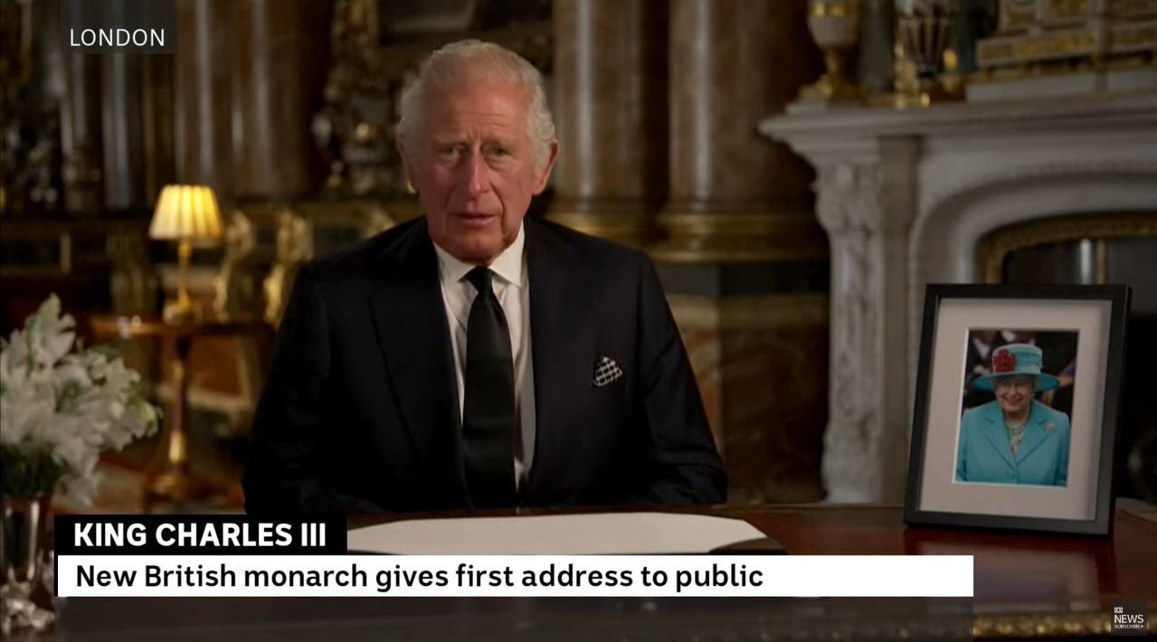 King Charles seated, delivering a video message after the death of Queen Elizabeth II