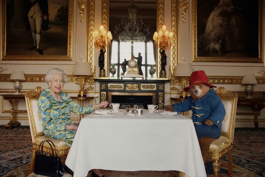 Winnie the Pooh and Queen Elizabeth II at a table. 