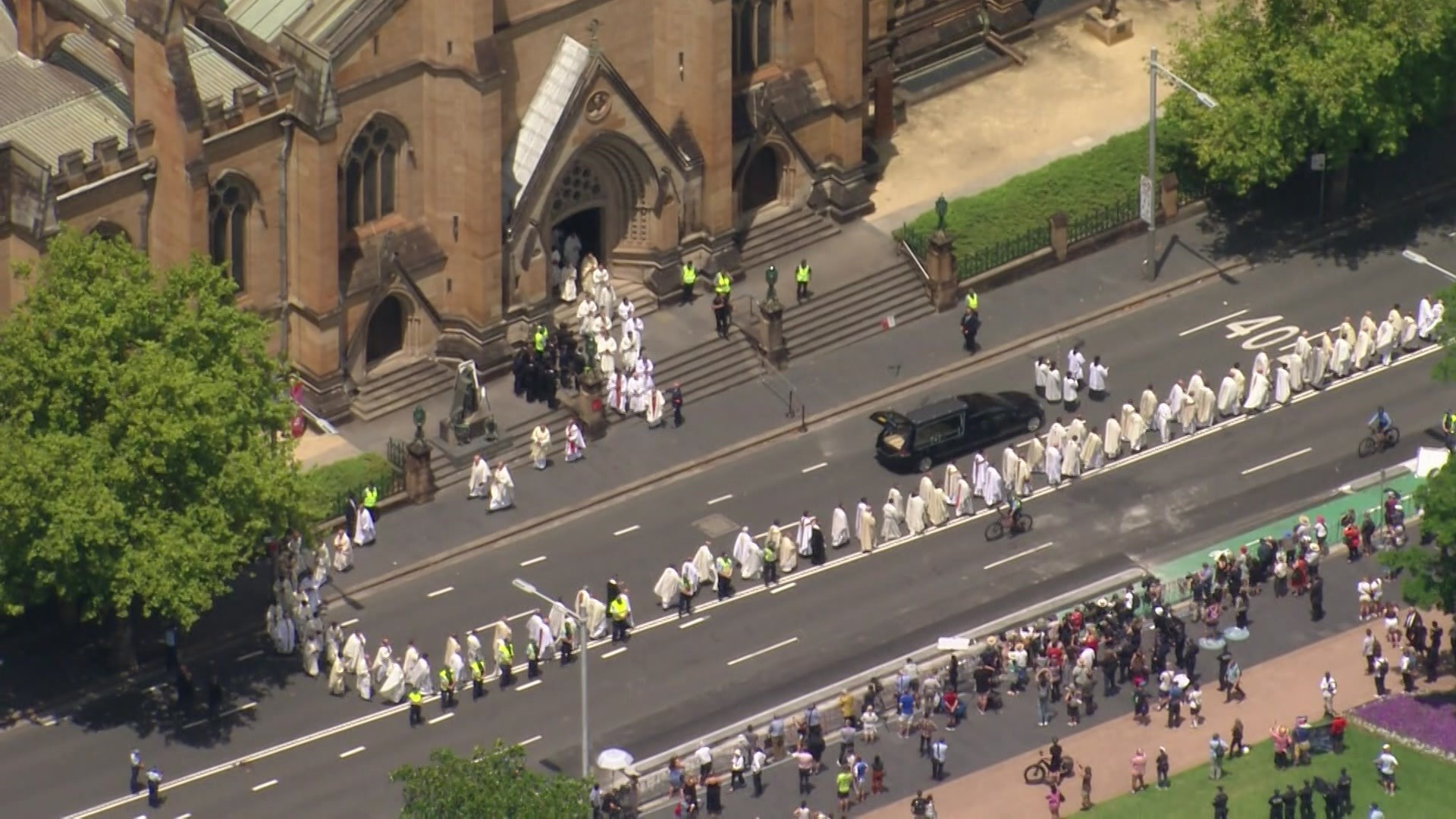 People in religious outfits stand around a hearse