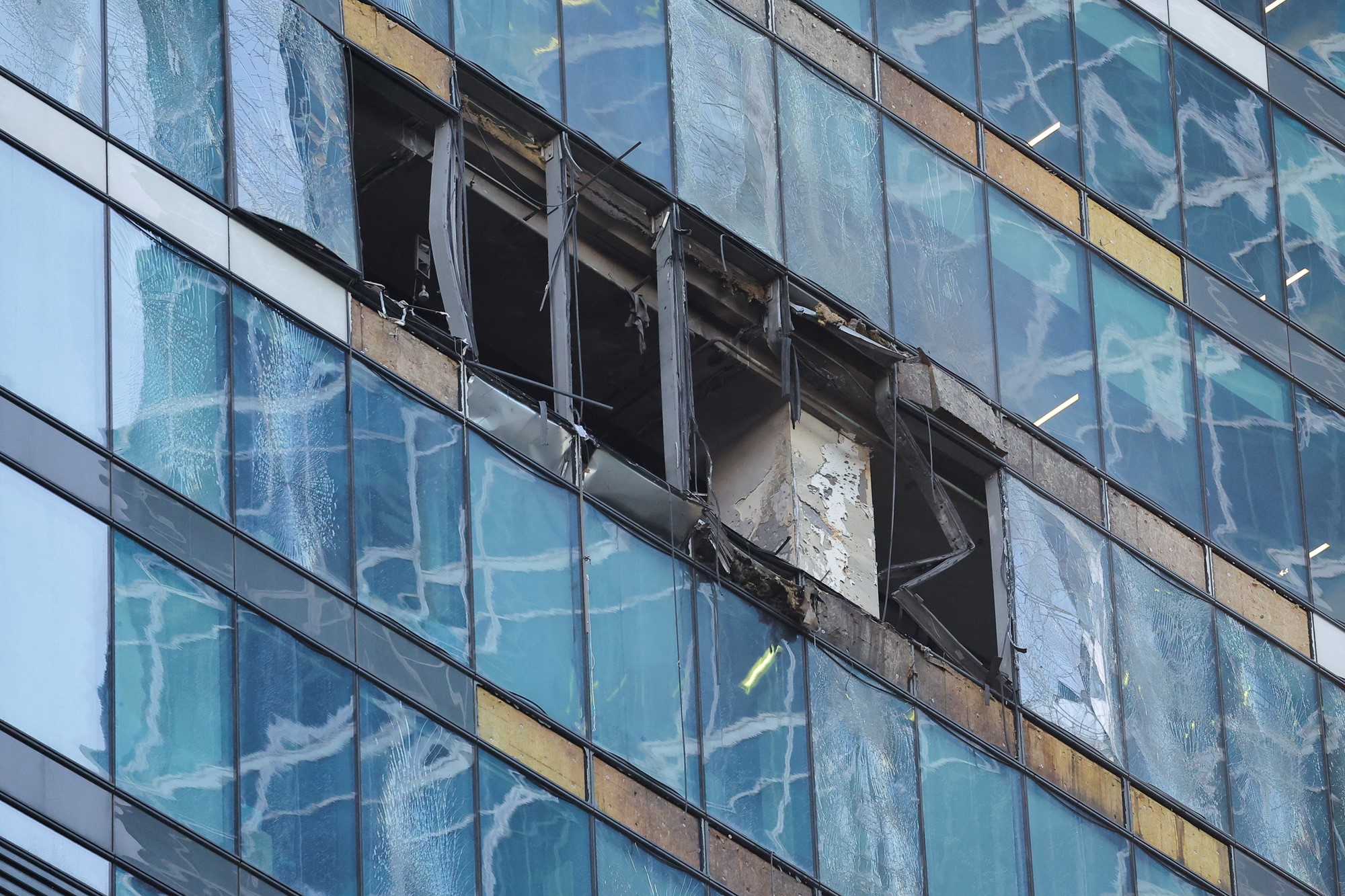 A close up of exterior glass windows of a skyscrapper wich have been badly damaged on a small number of floors