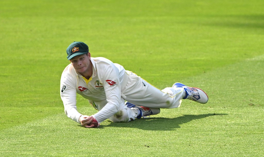 Australia fielder Steve Smith takes a catch on the grass.