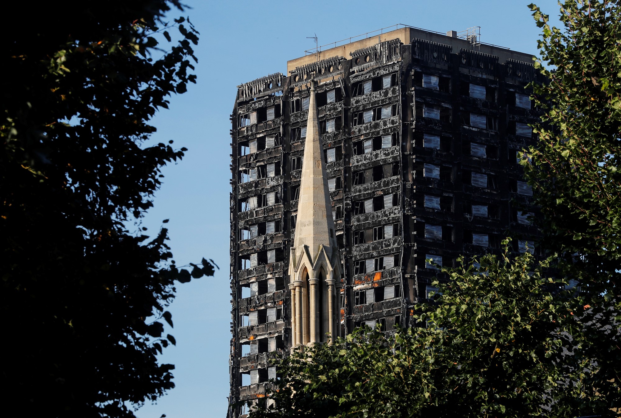 A burnt out apartment building seen between trees.