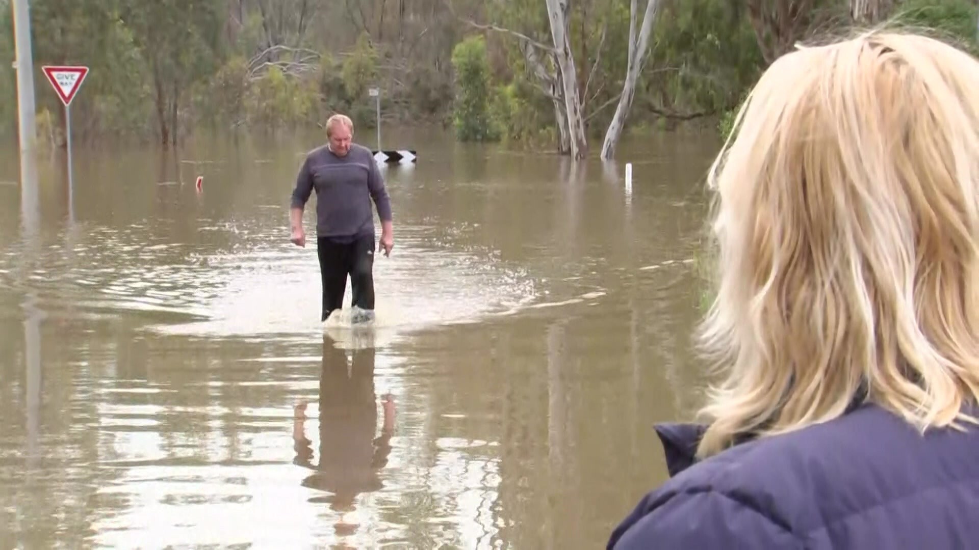 A man and woman standing in floodwaters.