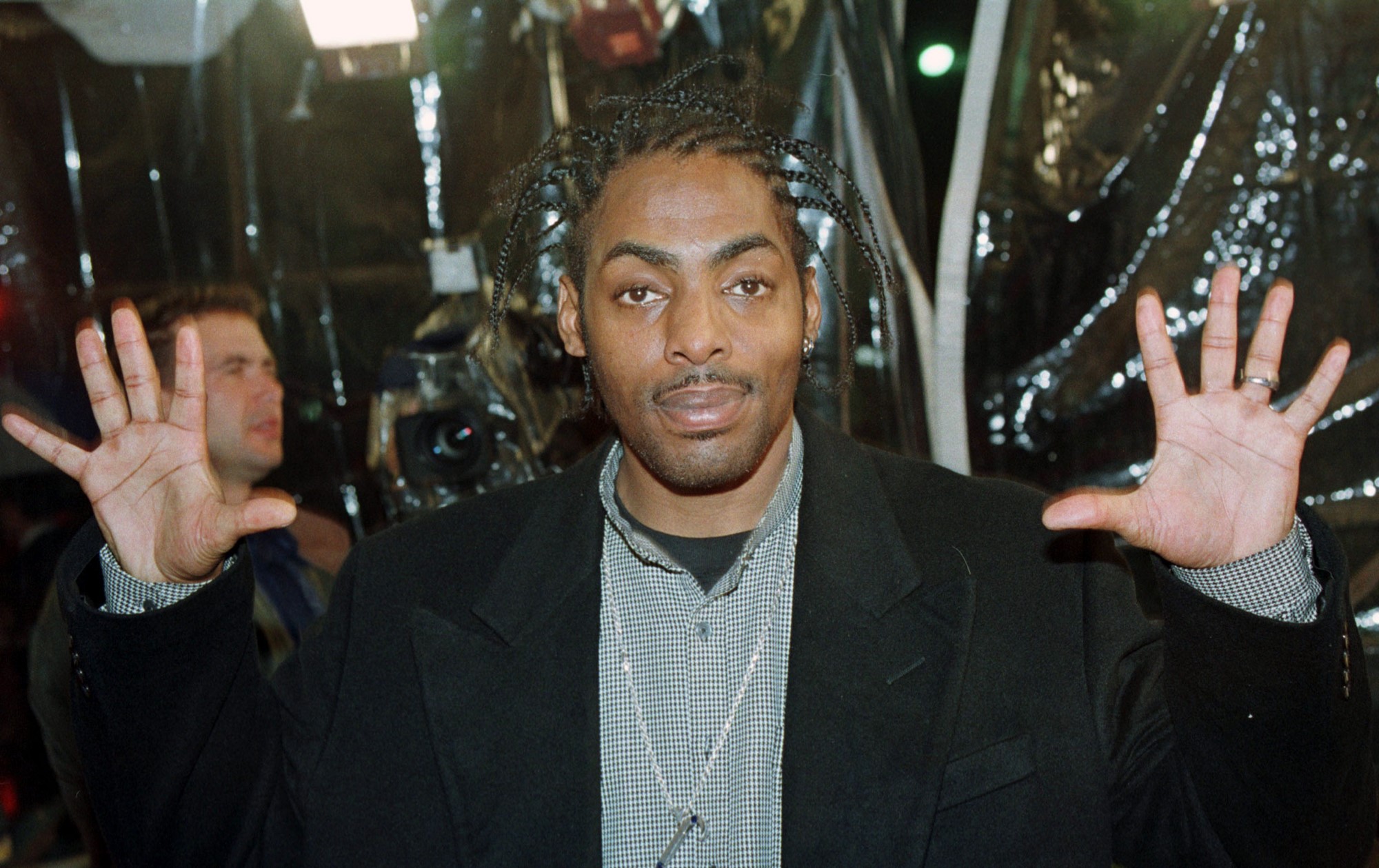 Coolio poses for a photo with his hands in the air.