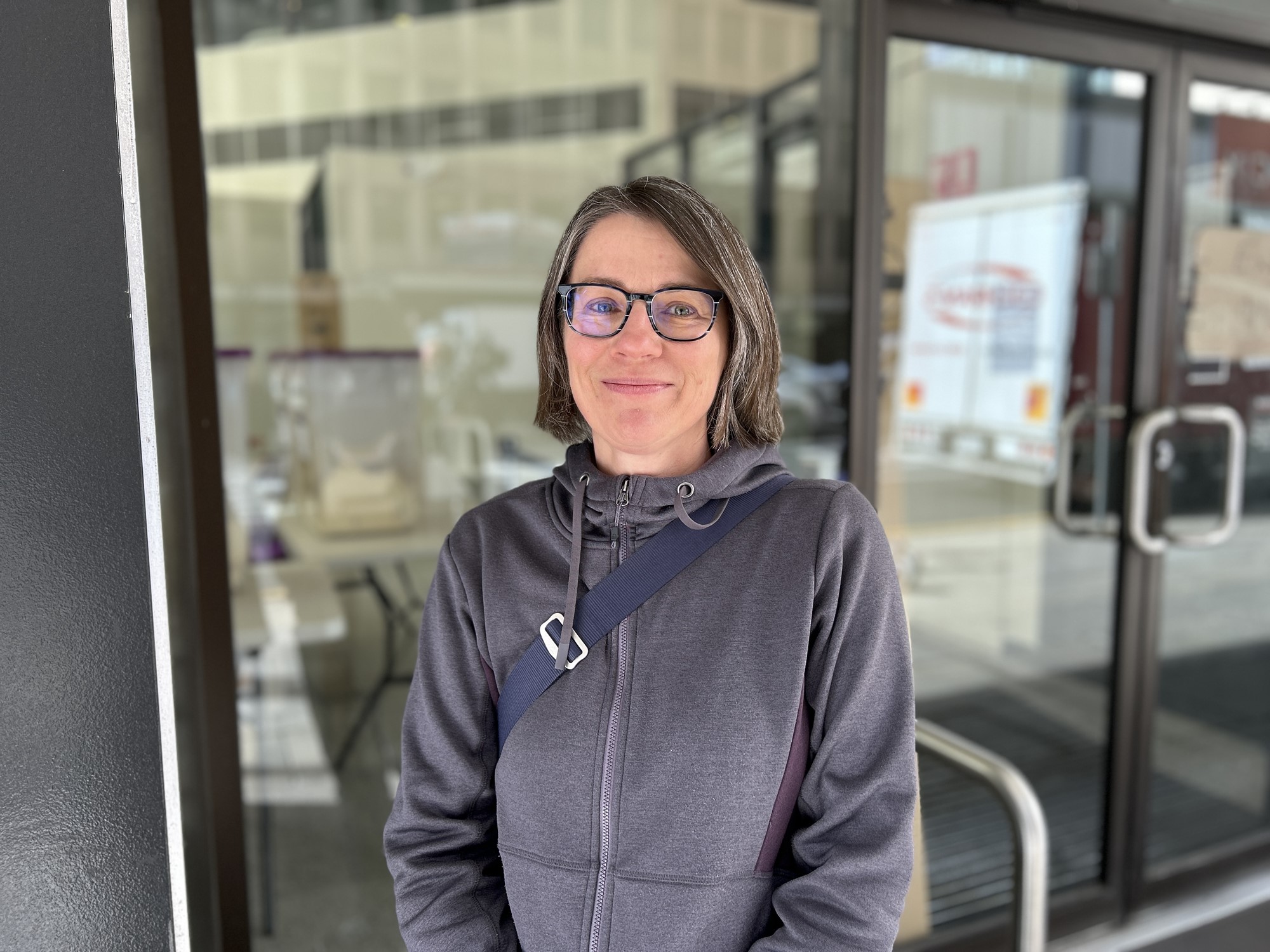 A woman with greying hair and glasses smiles for a photo.