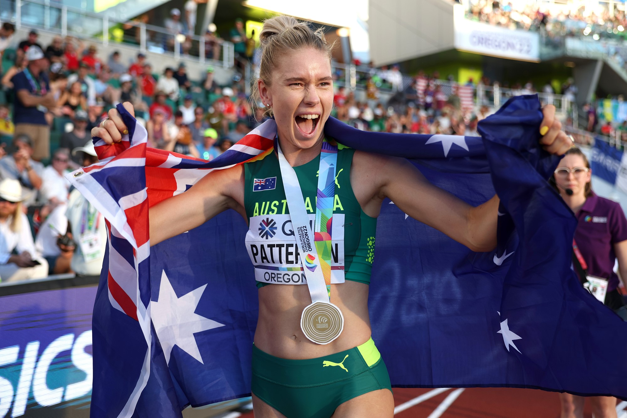 Eleanor Patterson smiles with an open mouth while wearing her high jump gold medal and draped in the Australian flag.