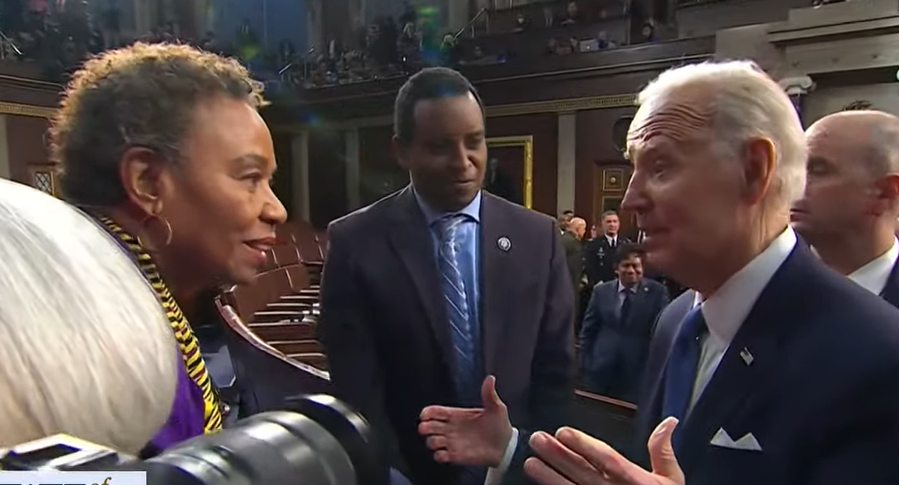 An elderly white man speaks to a middle-aged Black women on the House floor.