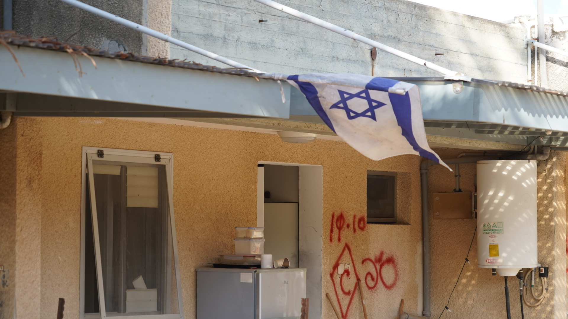 An israeli flag hangs off the side of a graffitied building