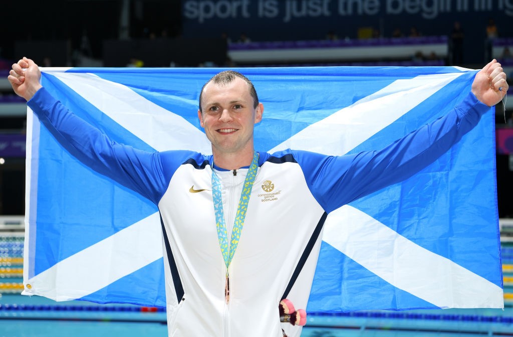A man holds a Scotland flag behind him