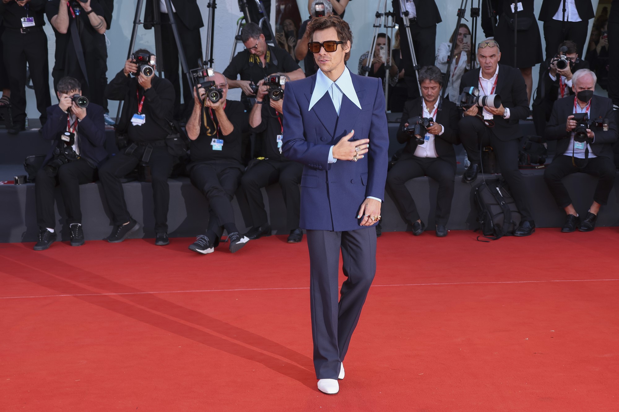 Harry Styles poses on red carpet wearing navy suit and shirt with oversized collar