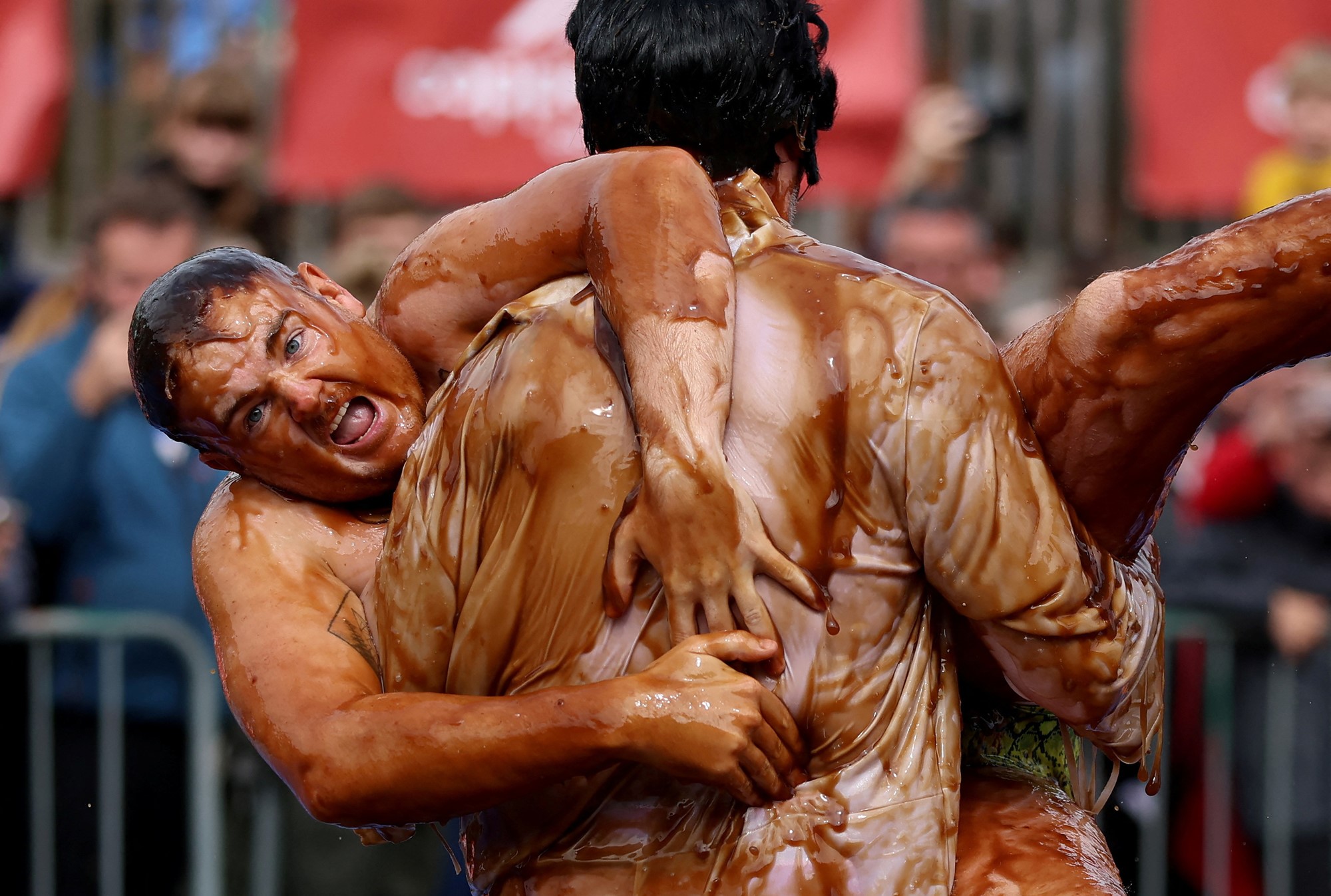 Two men covered in gravy wrestle