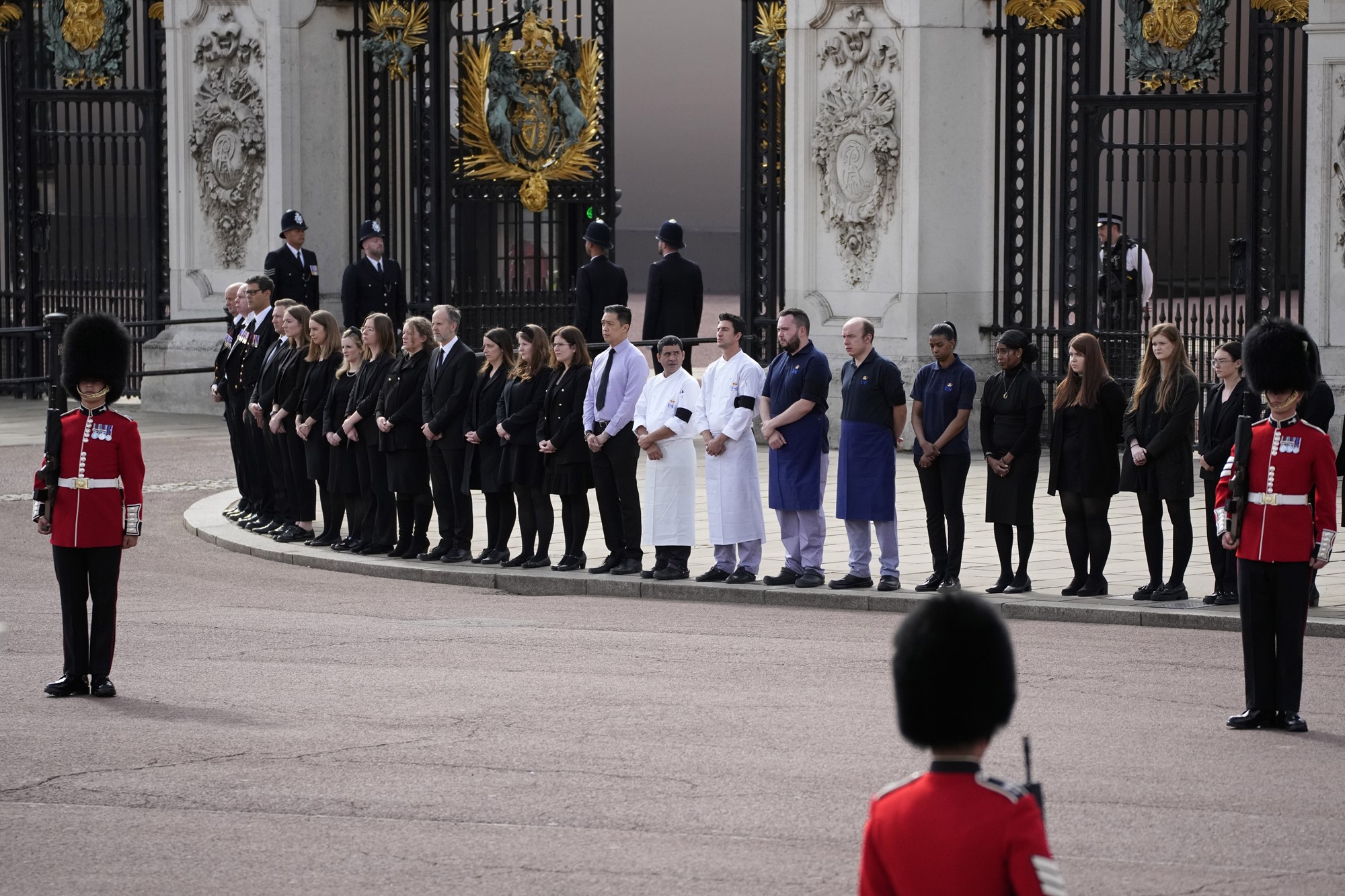 Royal staff members stand in a line on the street