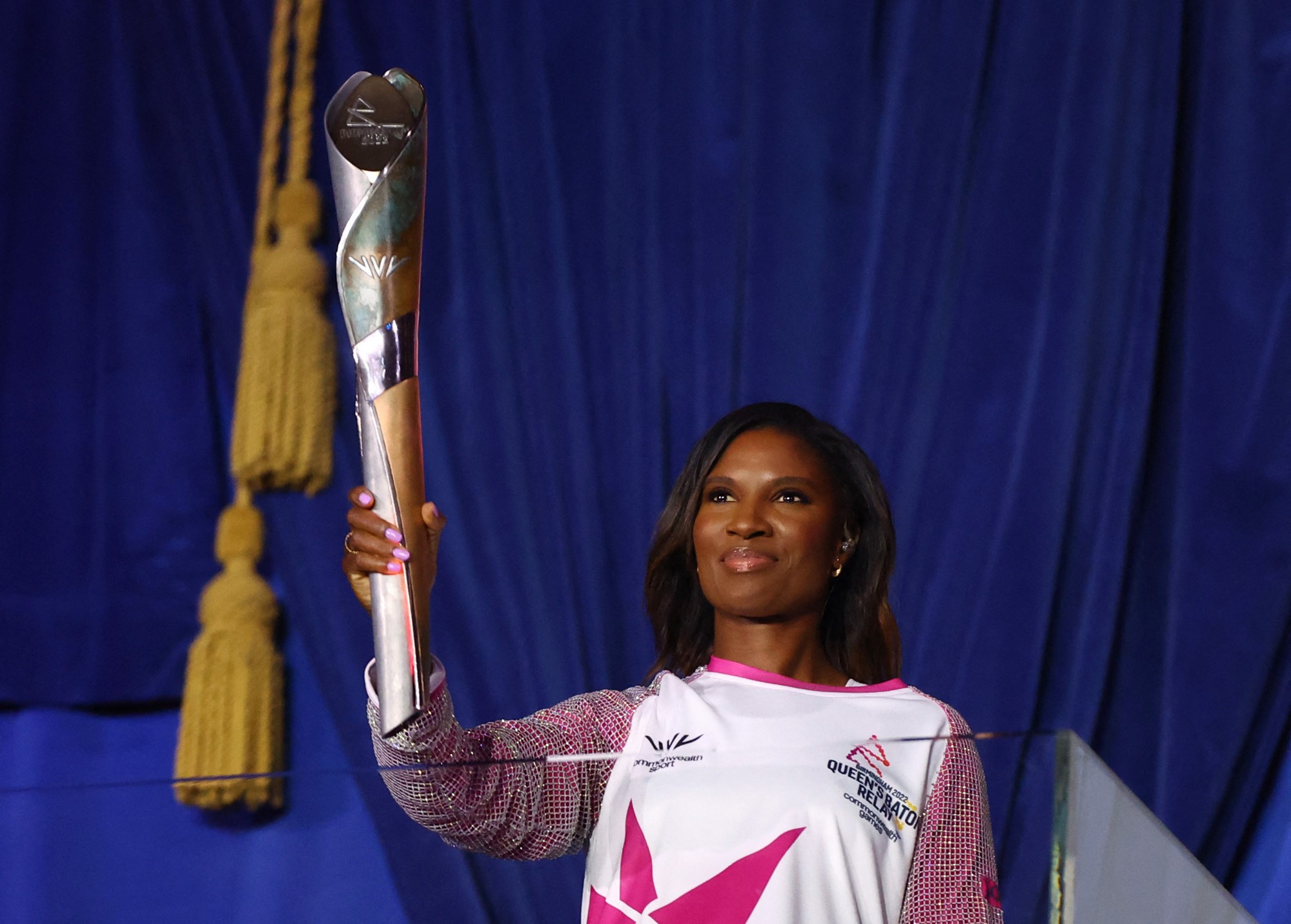 denise lewis holds the queen's baton