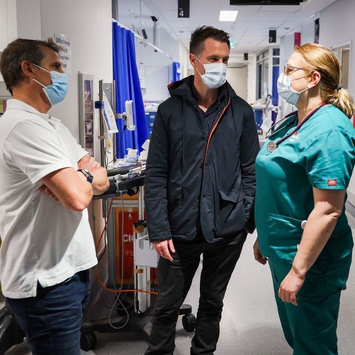 Chris Minns and Ryan Park talk to a woman in hosptial scrubs