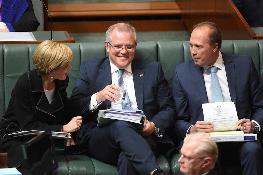 Morrison, sitting between Julie Bishop and Peter Dutton, grins in parliament.