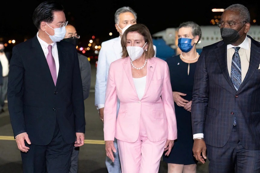 Nancy Pelosi in a pink suit and officials in masks on the tarmac