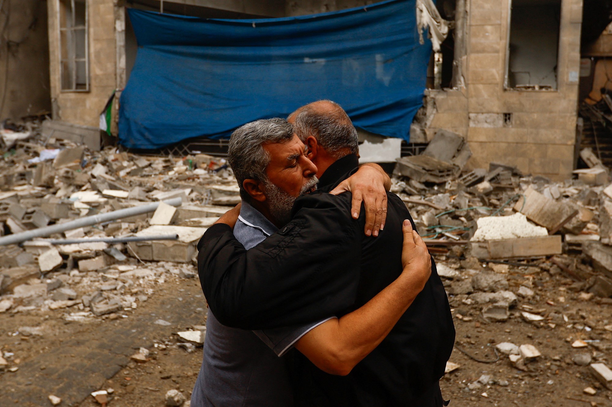 Palestinians embrace each other at the site of an Israeli strike on a mosque