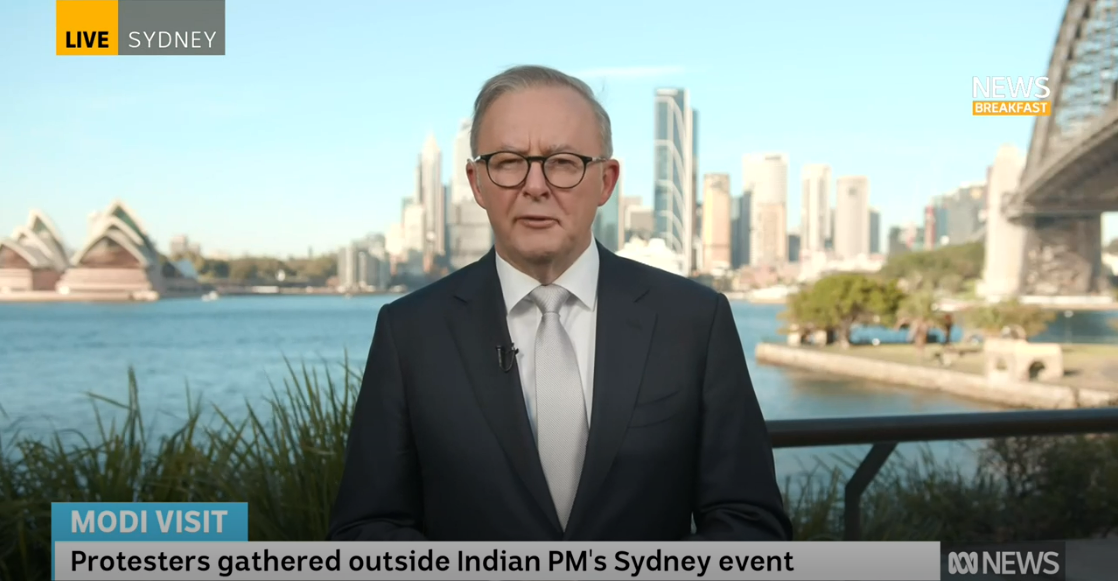 Anthony Albanese, speaking from Sydney Habour with the Opera House and Harbour Bridge in the background, wearing a suit