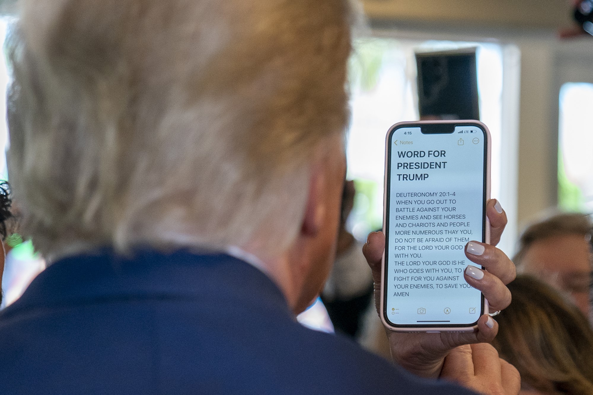 Donald Trump reads a message on a woman's phone as he visits Versailles.