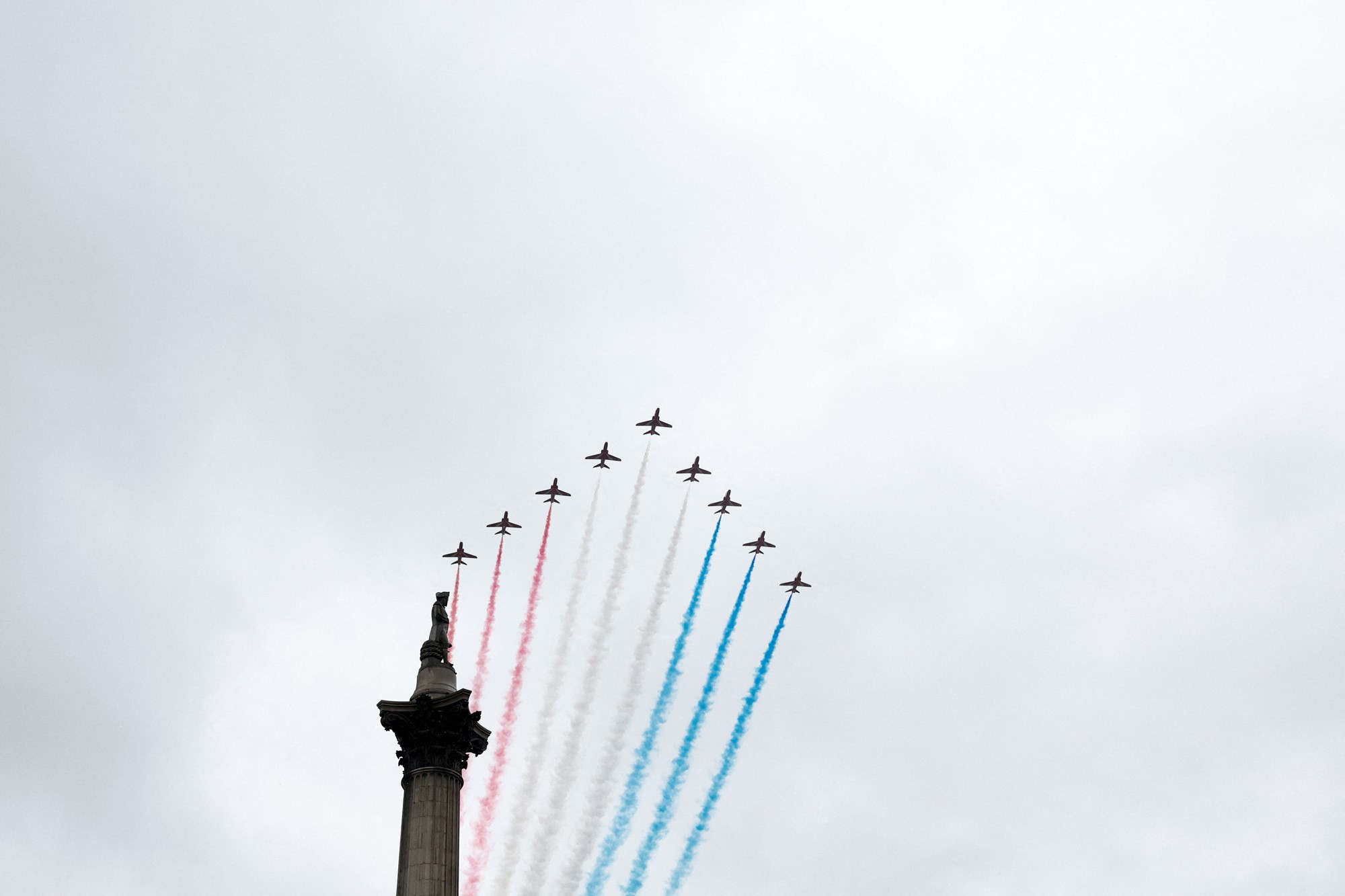 Jets with red, white and blue smoke fly through the air.