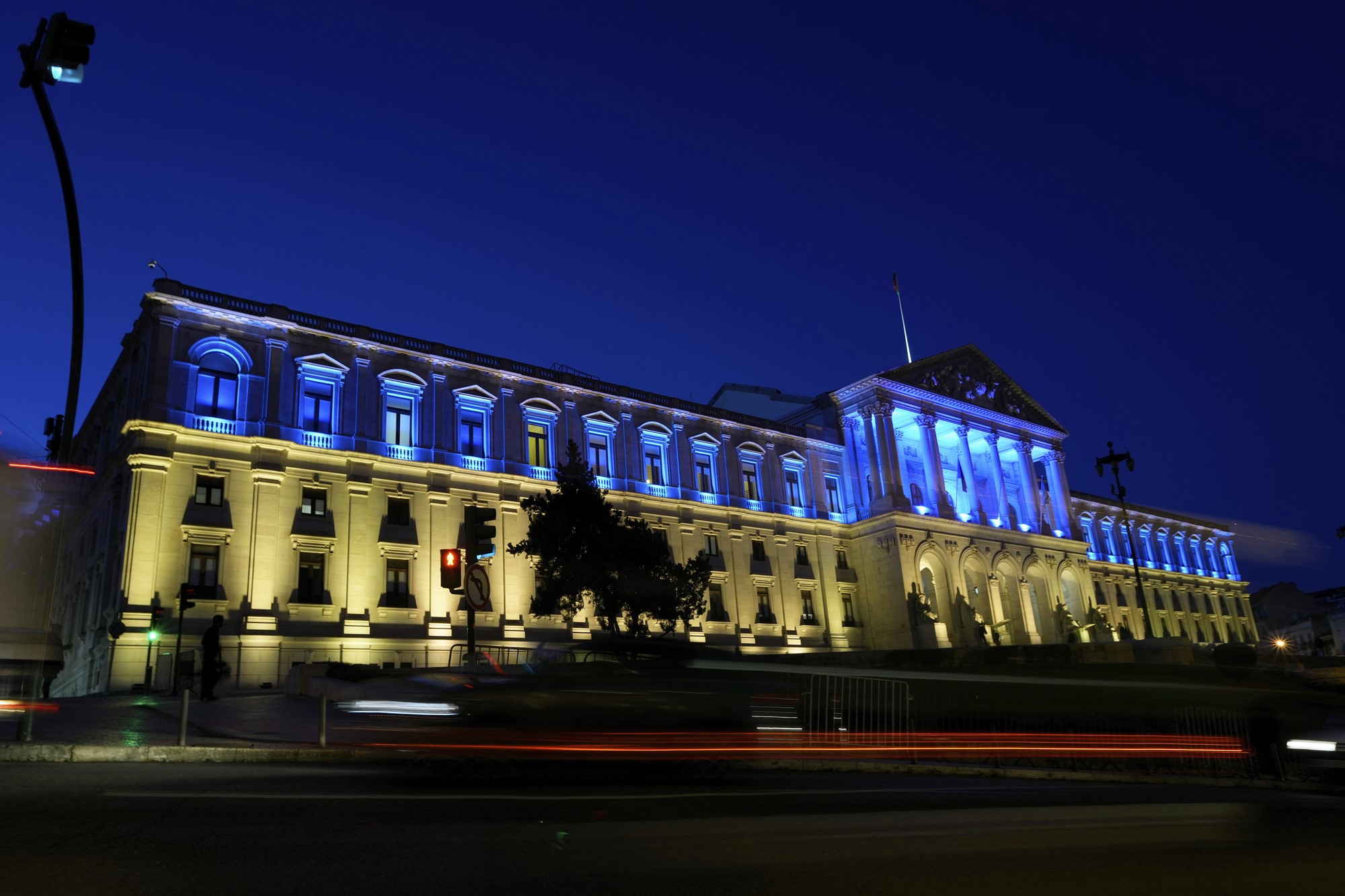 A government building lit up in blue and yellow.