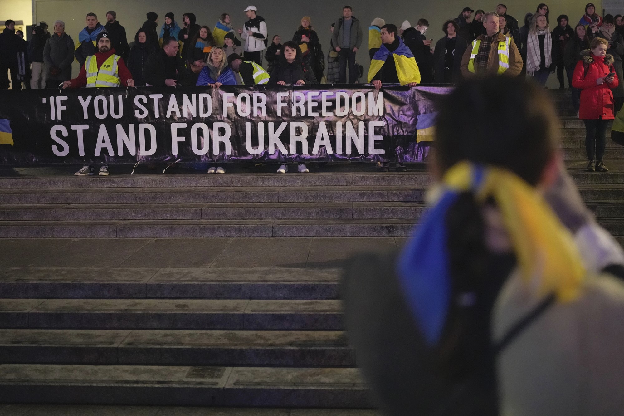 People hold a large banner reading if you stand for freedom stand for ukraine.