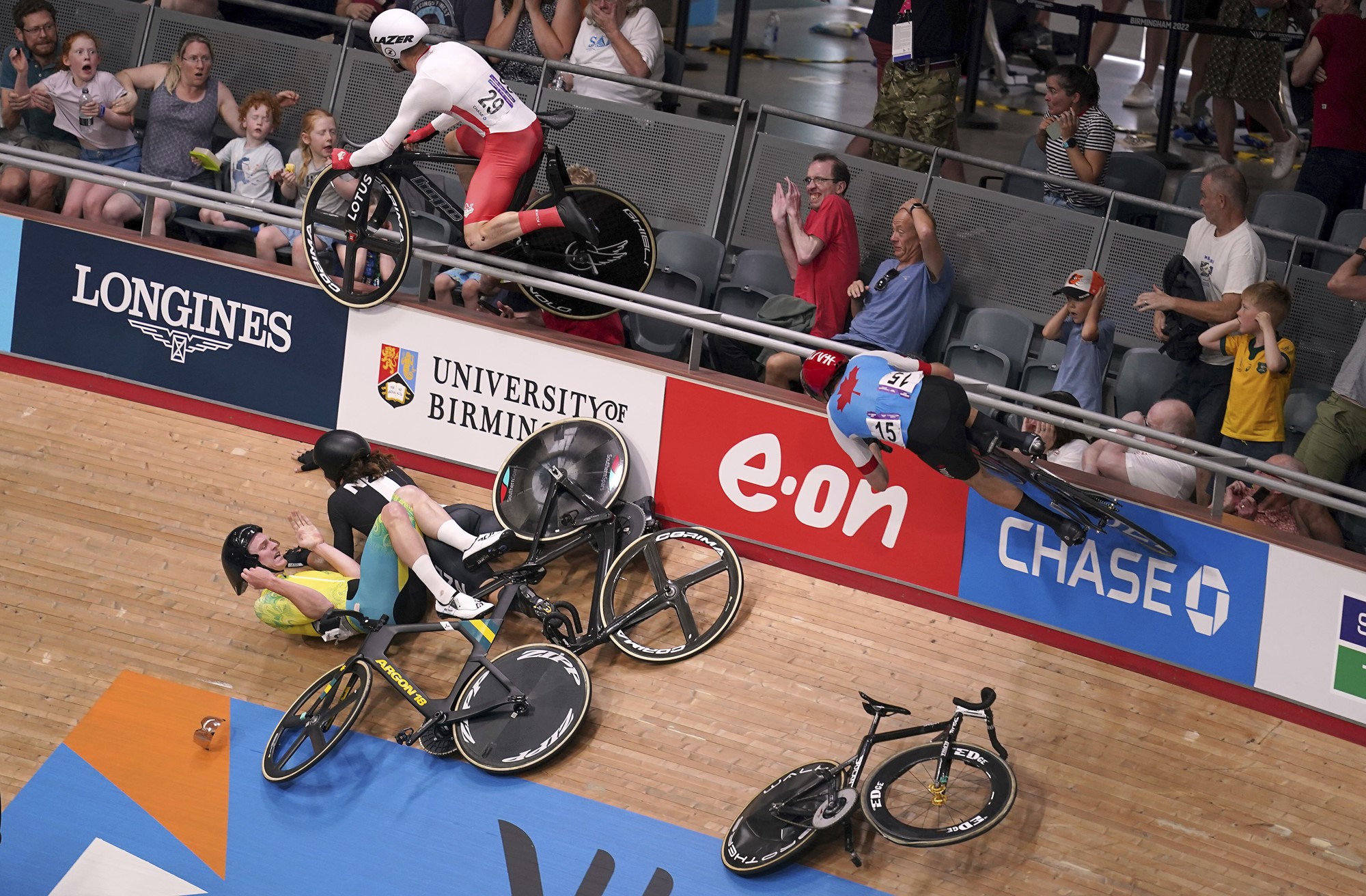 An English cyclist goes flying in the air towards the stands as crowds flinch and other cyclists lie on the track.