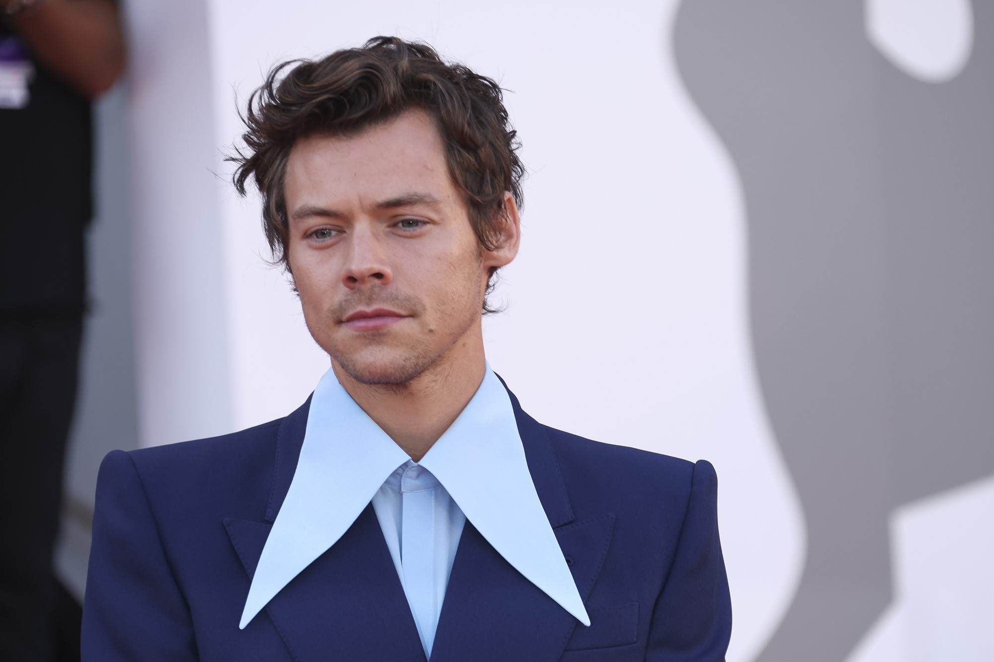 head-and-shoulders picture of harry styles posing on red carpet wearing shirt with oversized collar and suit jacket