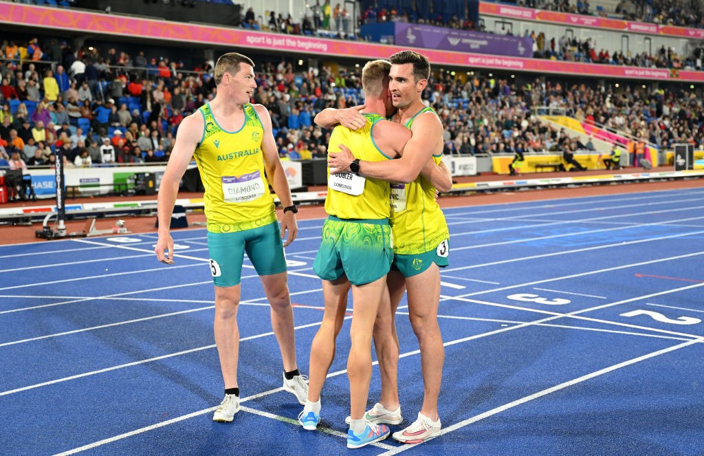 Thre Australian athletes in yellow singlets hug