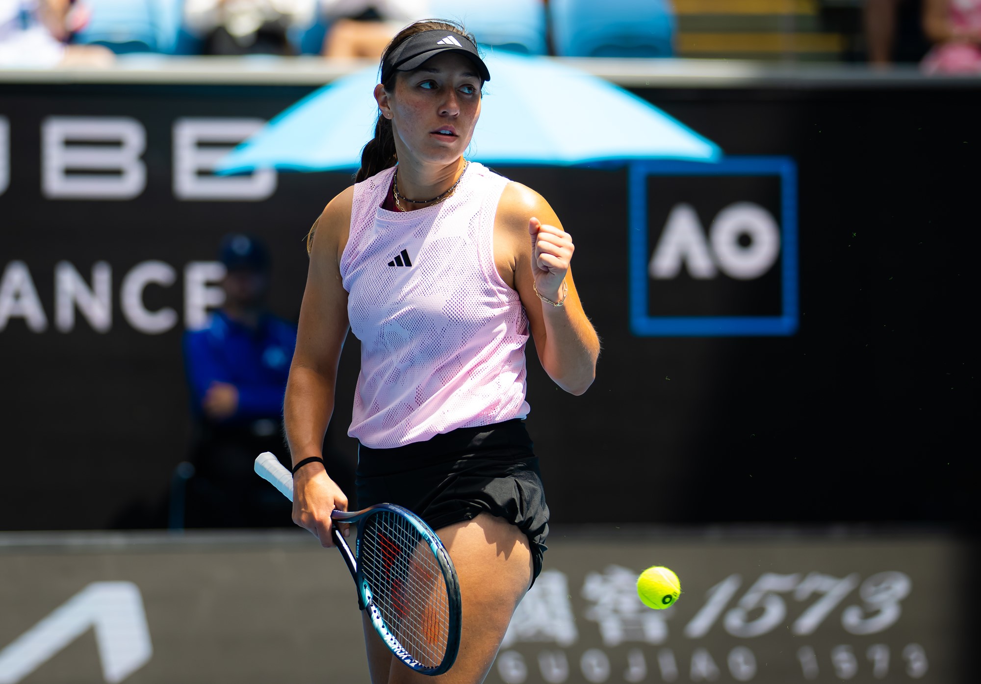 A women's tennis player clenches her fist