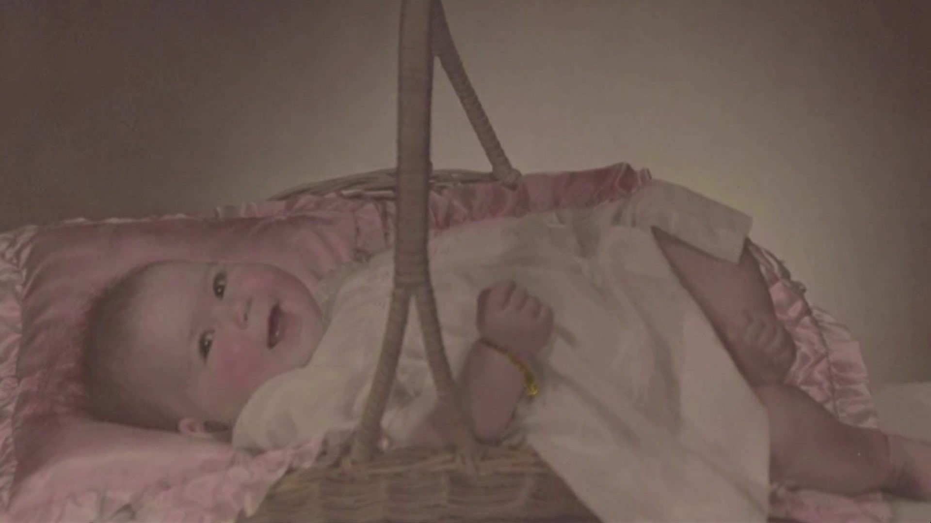 A baby lies in a basket.
