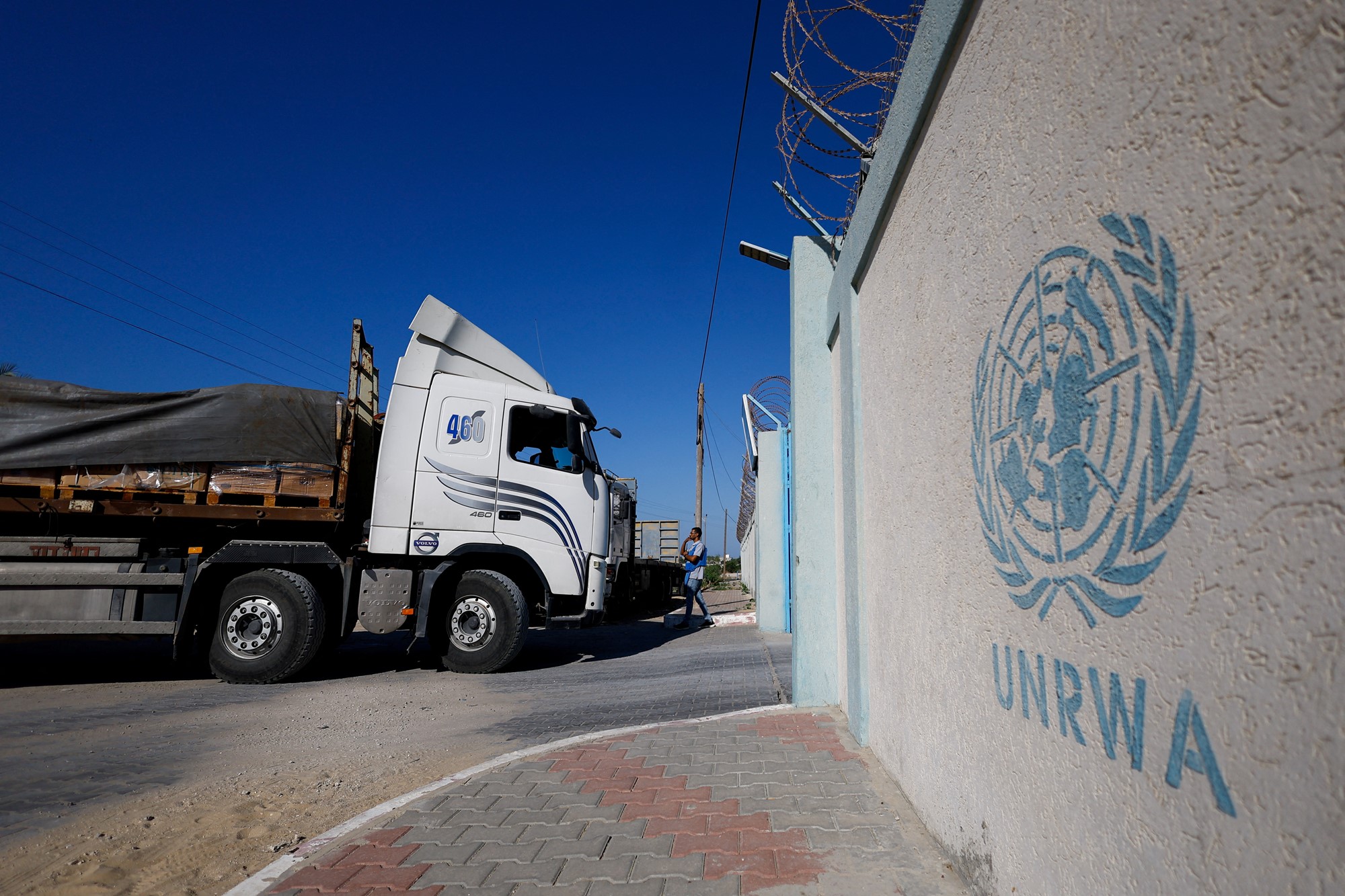 A truck is pictured in front of a wall that says UNRWA
