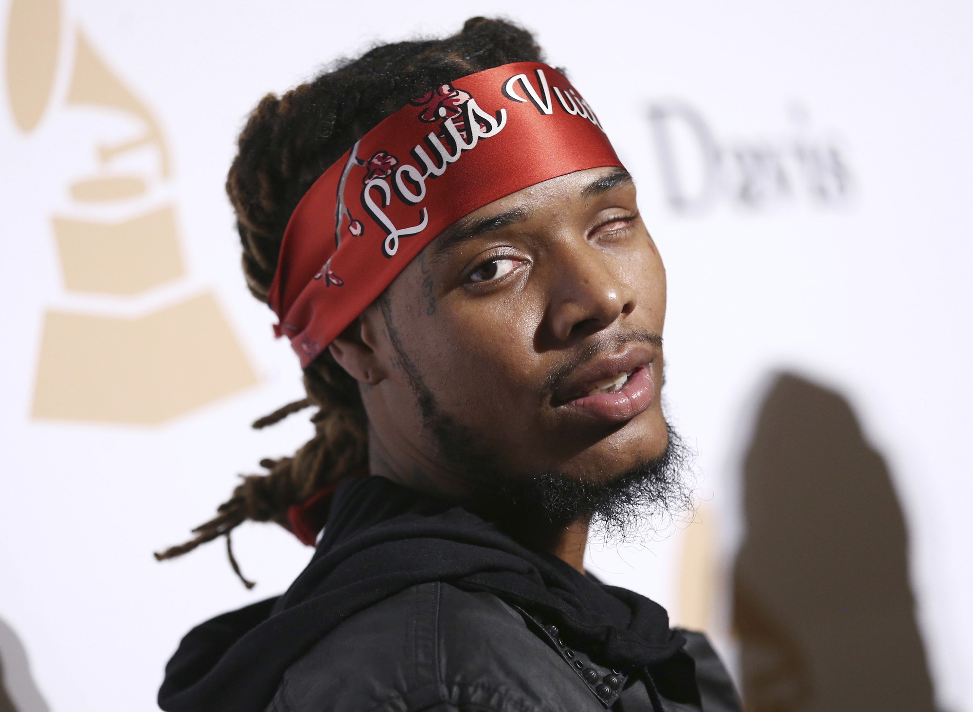 Rapper Fetty Wap, wearing a bandana, looks at the camera on a Grammys red carpet