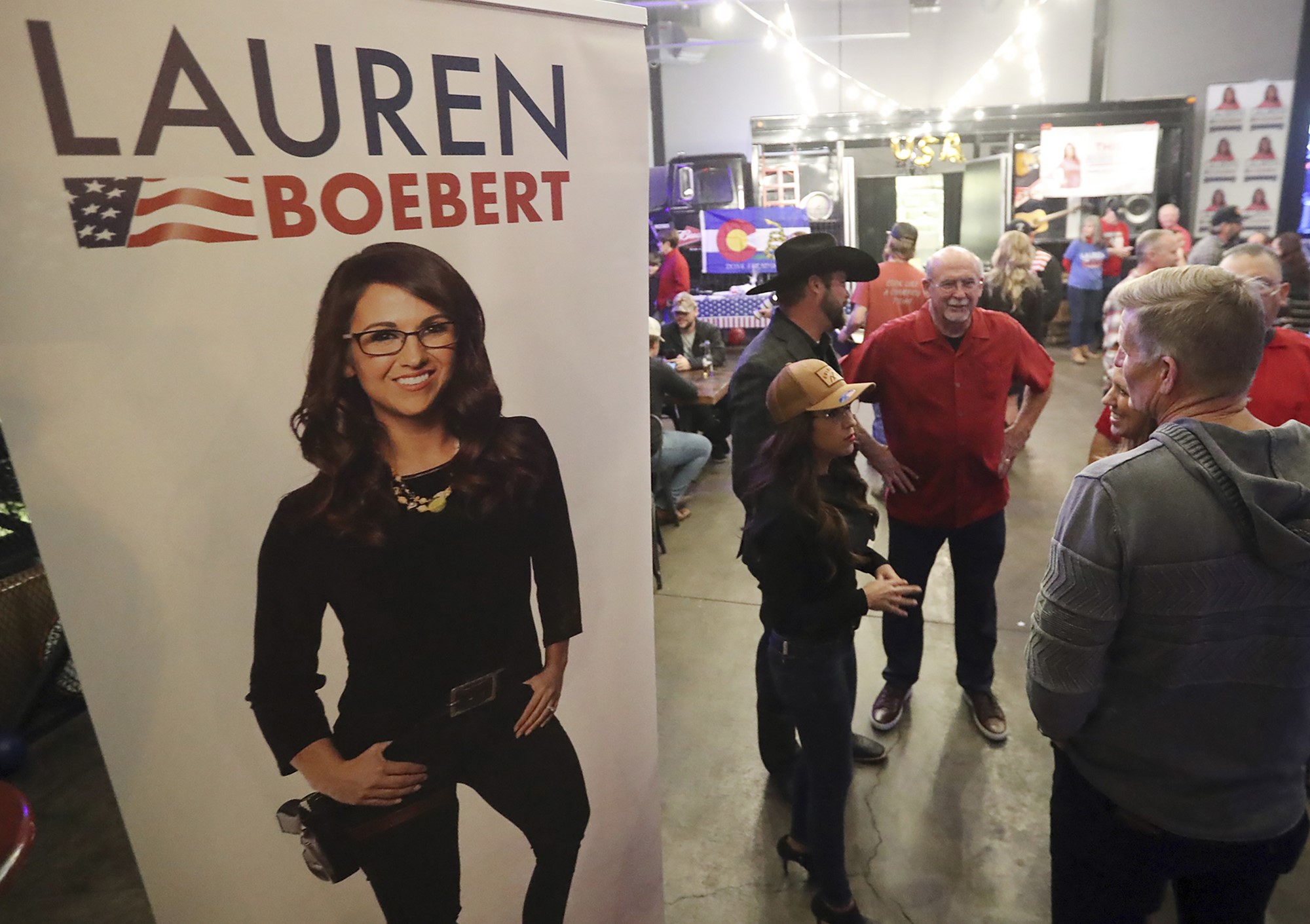Supporters mill around a Lauren Boebert sign during midterm election night.