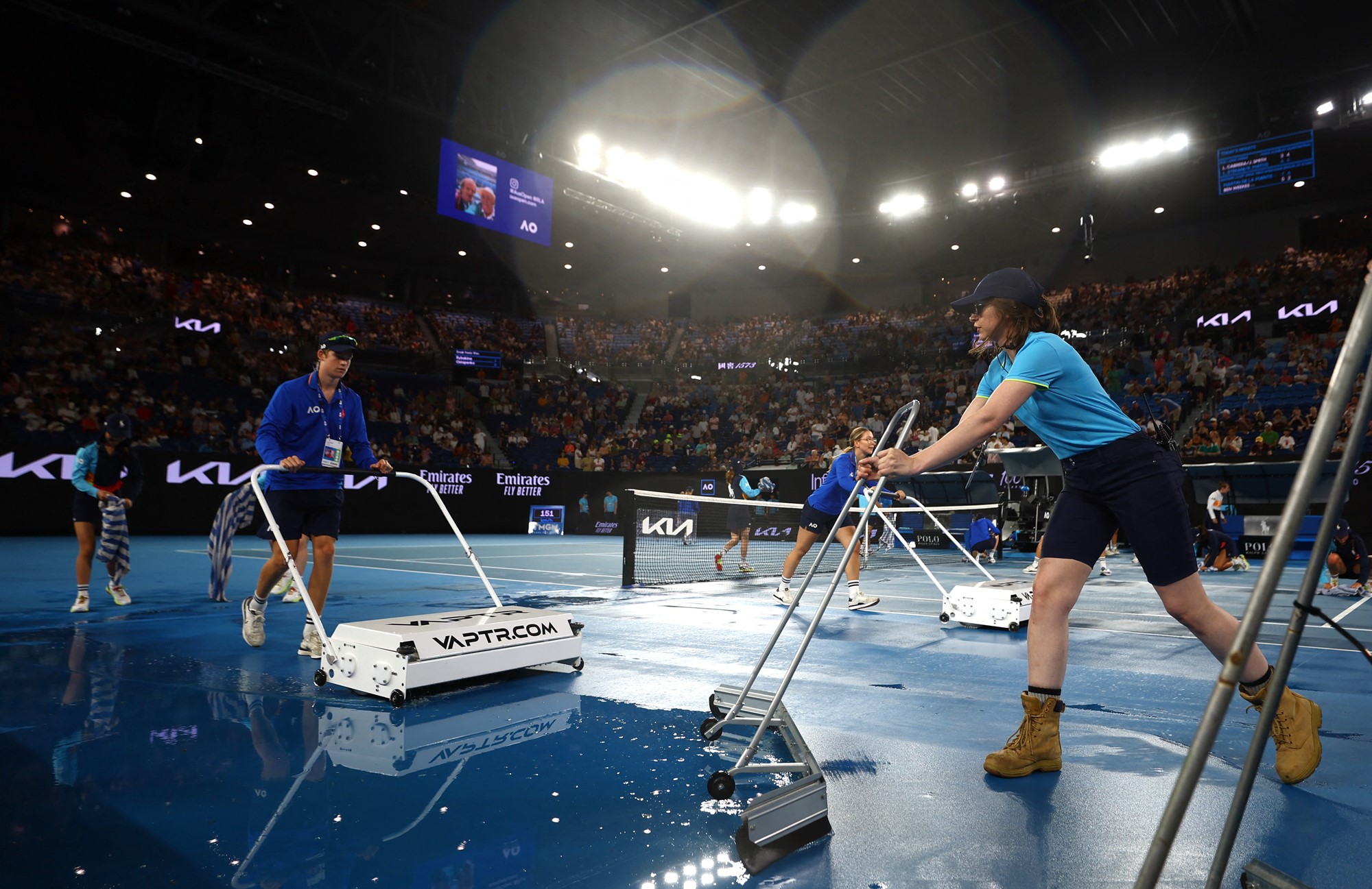 Ballkids and tournament staff dry Rod Laver Arena.
