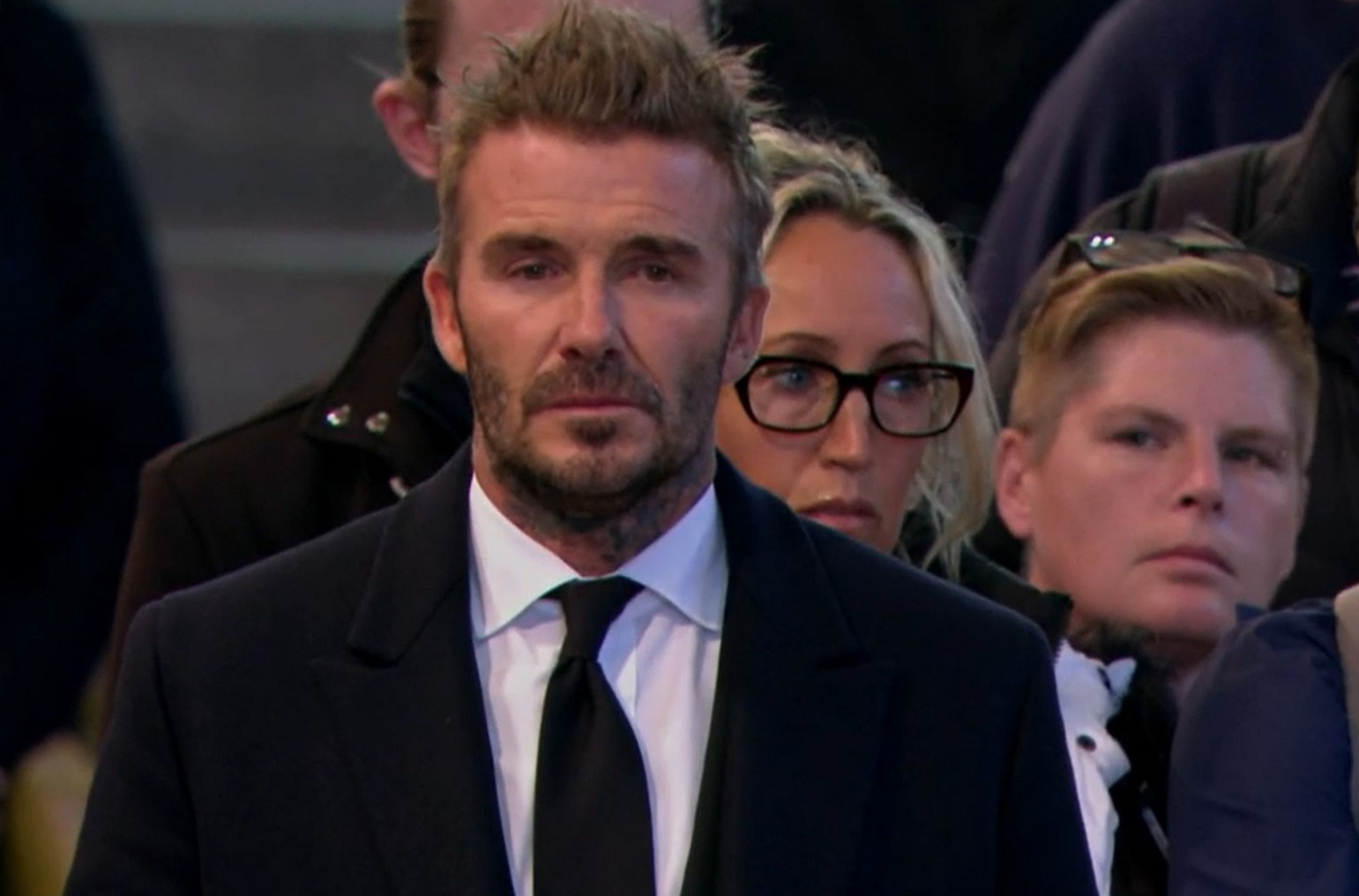 A man in a suit and tie stands in a hall.