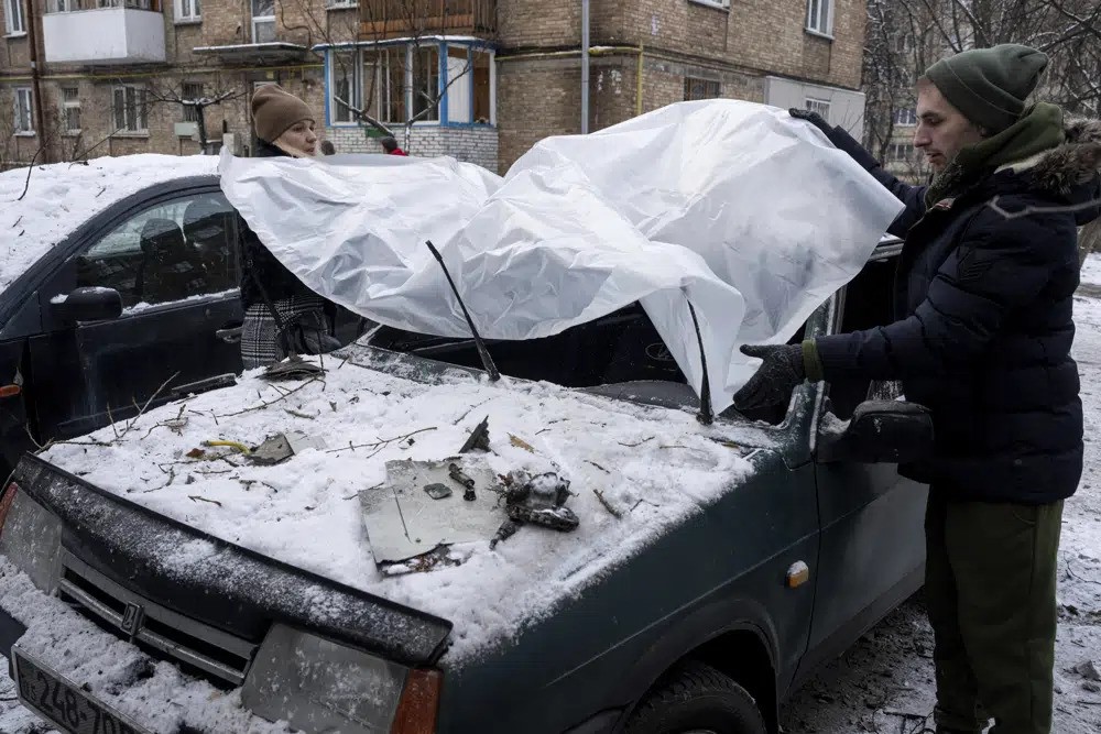 A couple cover their car with a tarp after it was damaged by strikes.