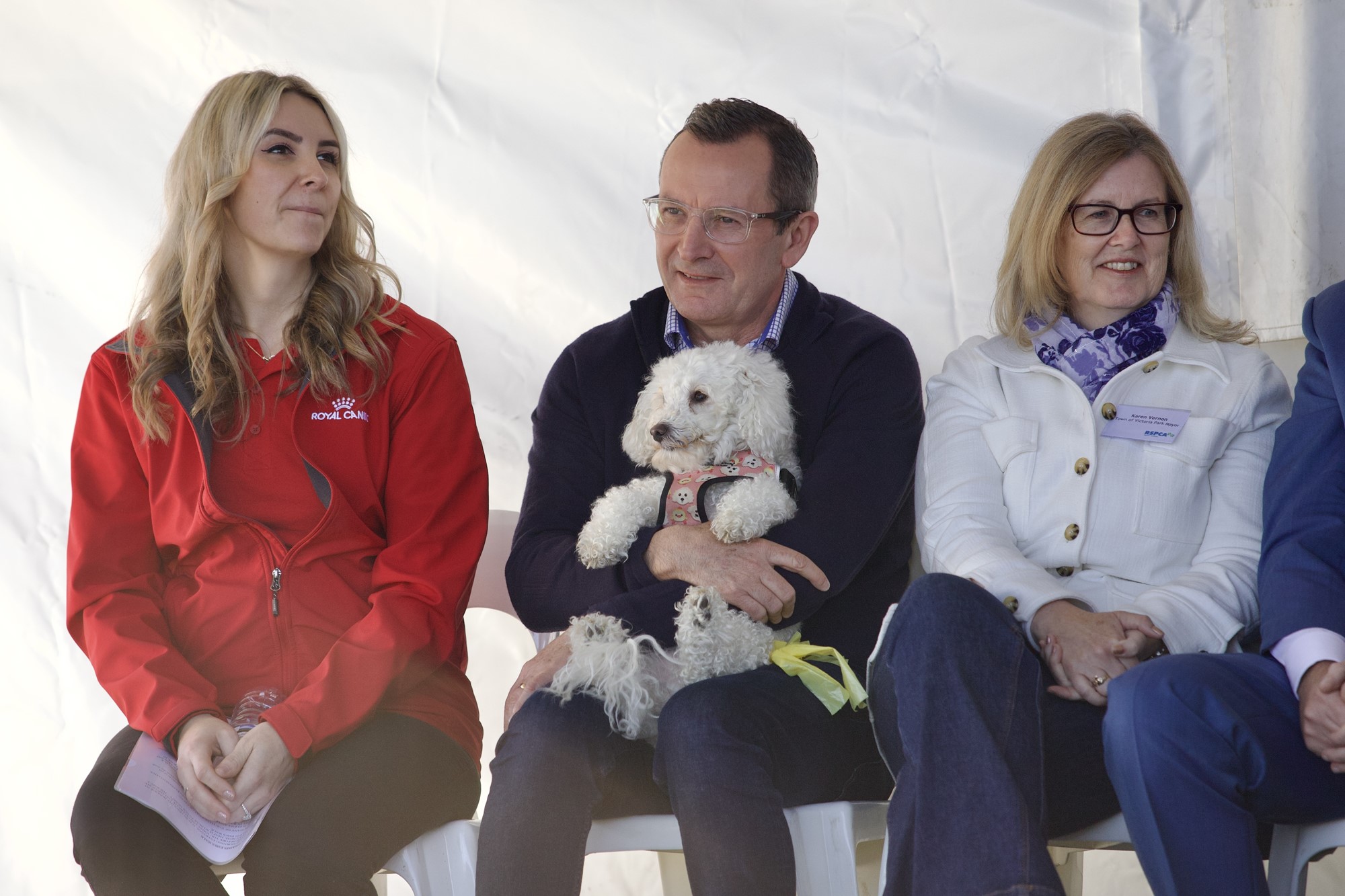 A man sits on a bench with women cuddling a dog