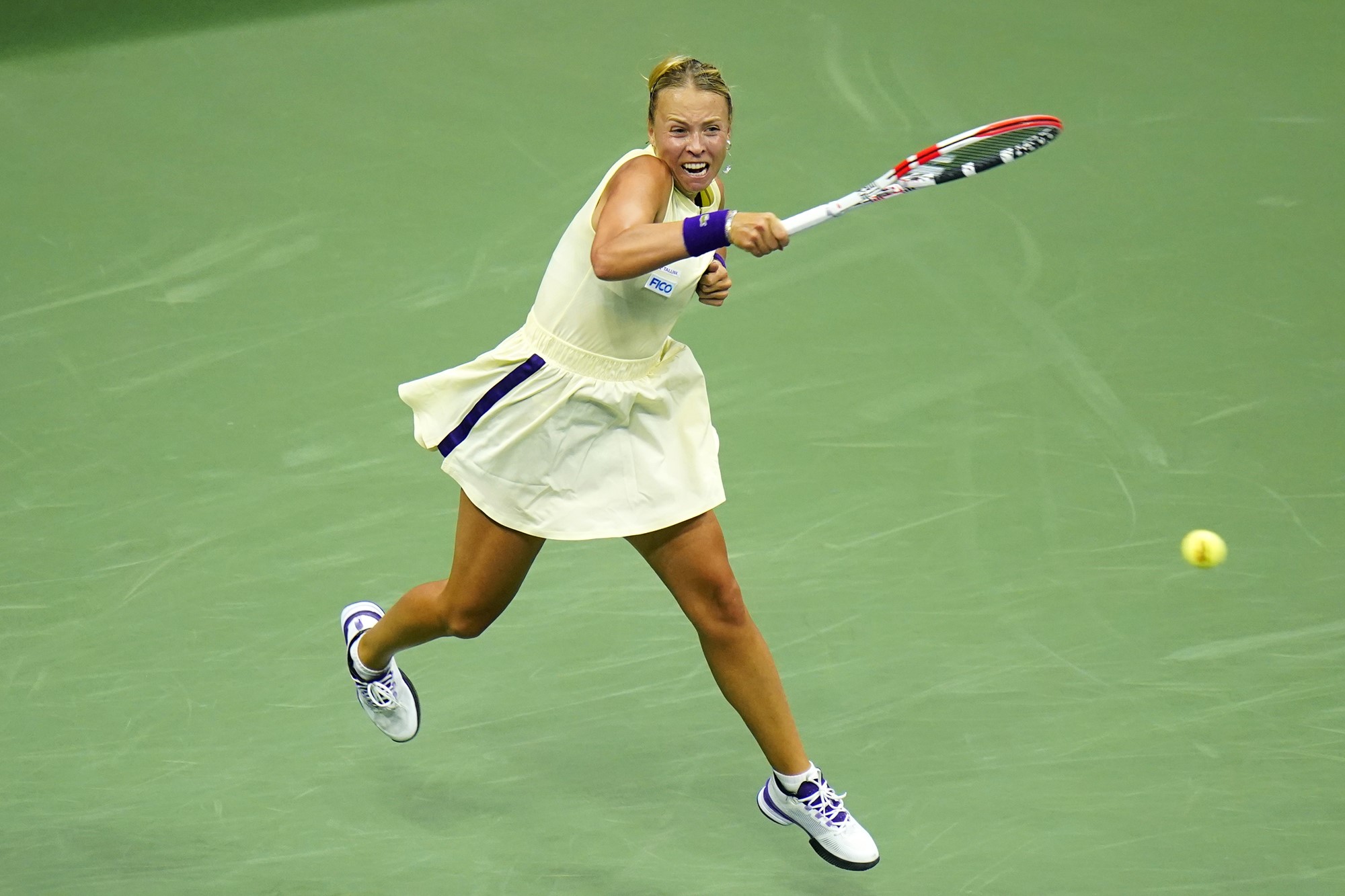 A woman in a green tennis outfit hits the ball with a raquet.