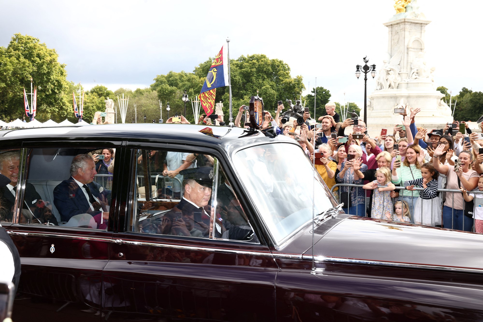 King Charles III greets supporters from a car as he arrives to Buckingham Palace