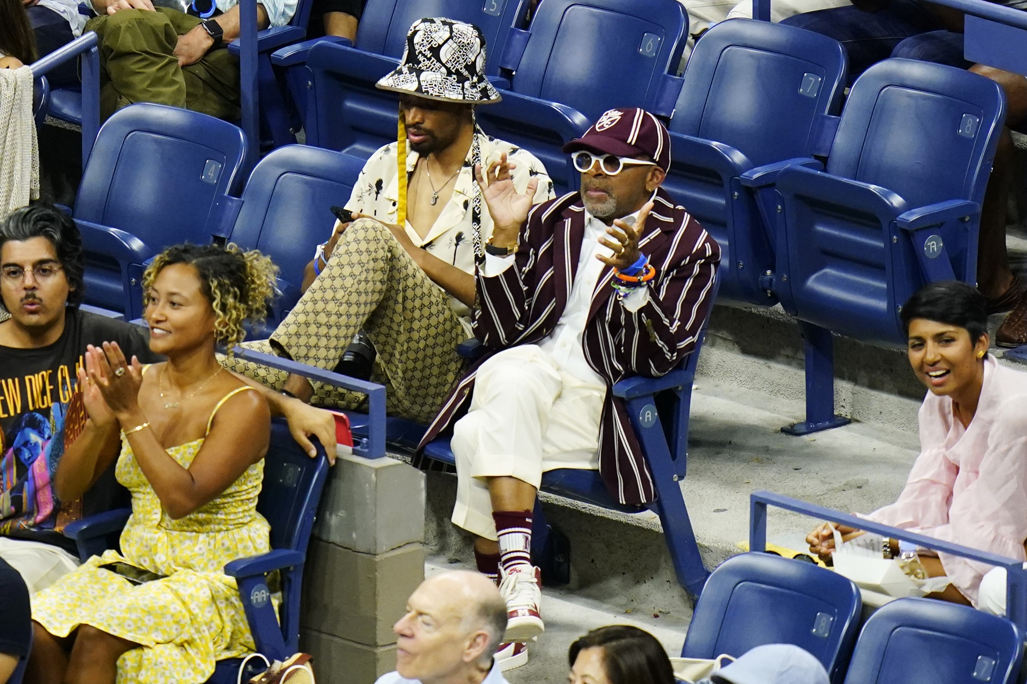 A man in a maroon baggy cap and striped blazer sits in the crowd.