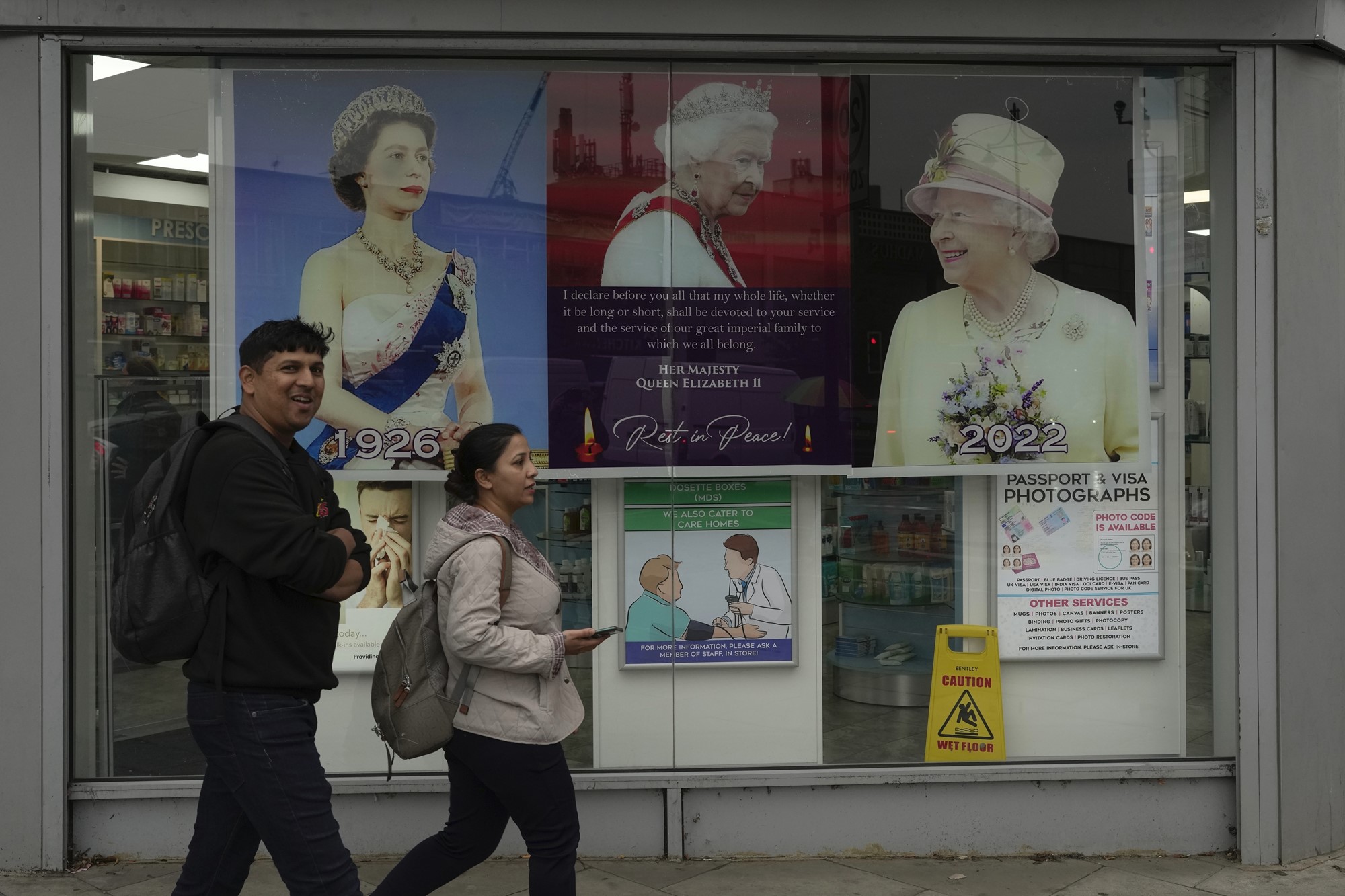 Mężczyzna i kobieta przechodzą przez okno z obrazami królowej Elżbiety