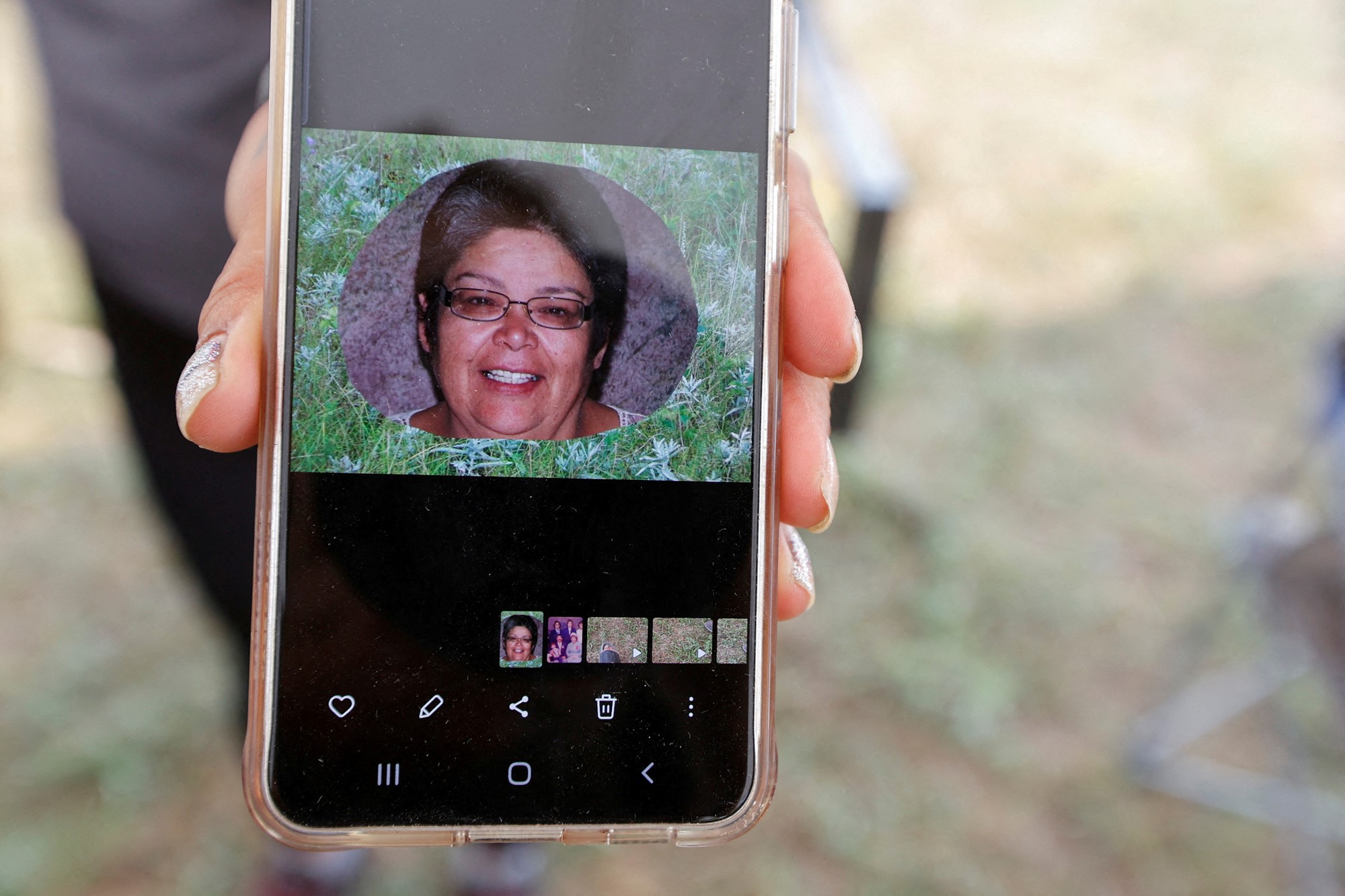 a person holds a mobile phone showing a picture of a woman smiling