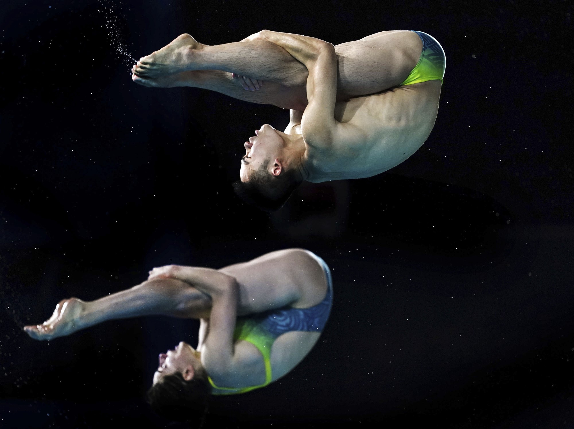 Shixin Li and Maddison Keeney grab the back of their legs as they flip during a synchronised dive.