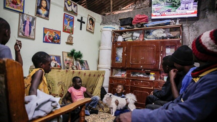 Children sit around a TV watching the Queen's funeral