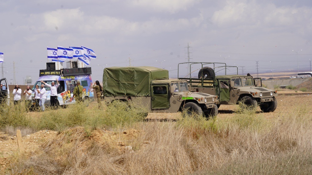 Military vehicles and a van with Israel flags