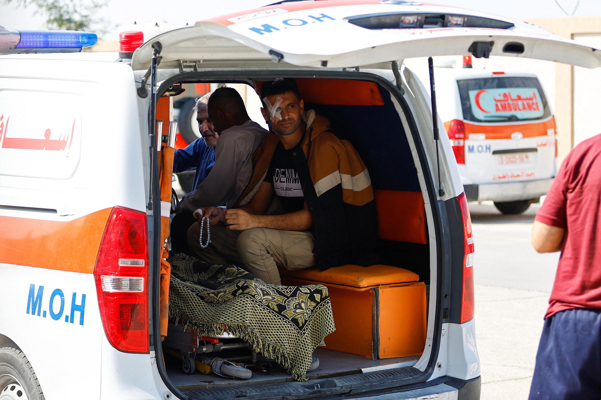Man with patch on eye sits in the back of an ambulance