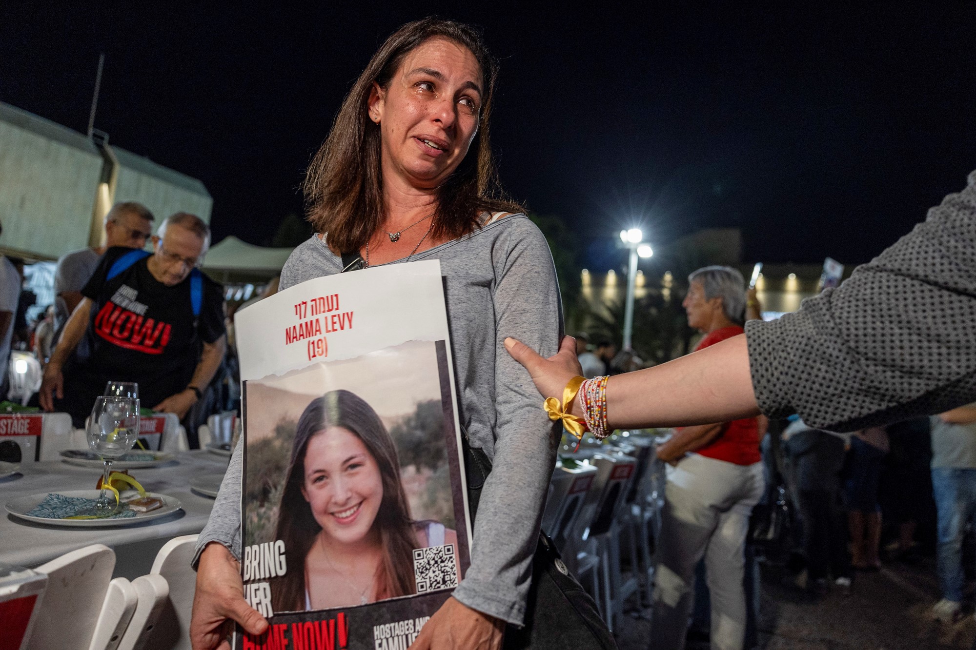 a distraught woman holds up a poster of her daughter