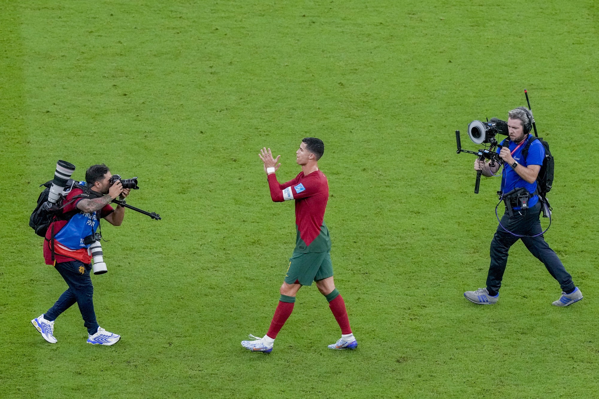 Cristiano Ronaldo applauds fans after Portugal's win over Switzerland at the Qatar World Cup. Two cameramen follow him.