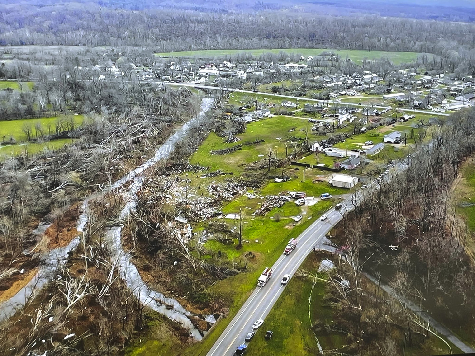 An aerial shot of ahighway where buildinigs and trees have been destroyed.